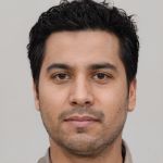 face of a man with dark hair, dark eyes and stubble.