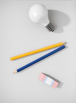 bulb, two pencils and a rubber on a piece of paper. 